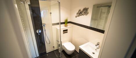 Un baño moderno con cabina de ducha de vidrio, inodoro y lavamanos.