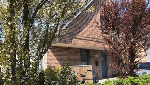 A brick building with a small porch, a bicycle, and a mailbox. - Abendsonne (Sylt)