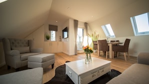 Una sala de estar moderna estilo loft con techo alto, comedor y un gran ventanal que proporciona luz natural.