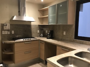 Prepare meals in a well-equipped kitchen with a gas stove, blender, and ample counter space.