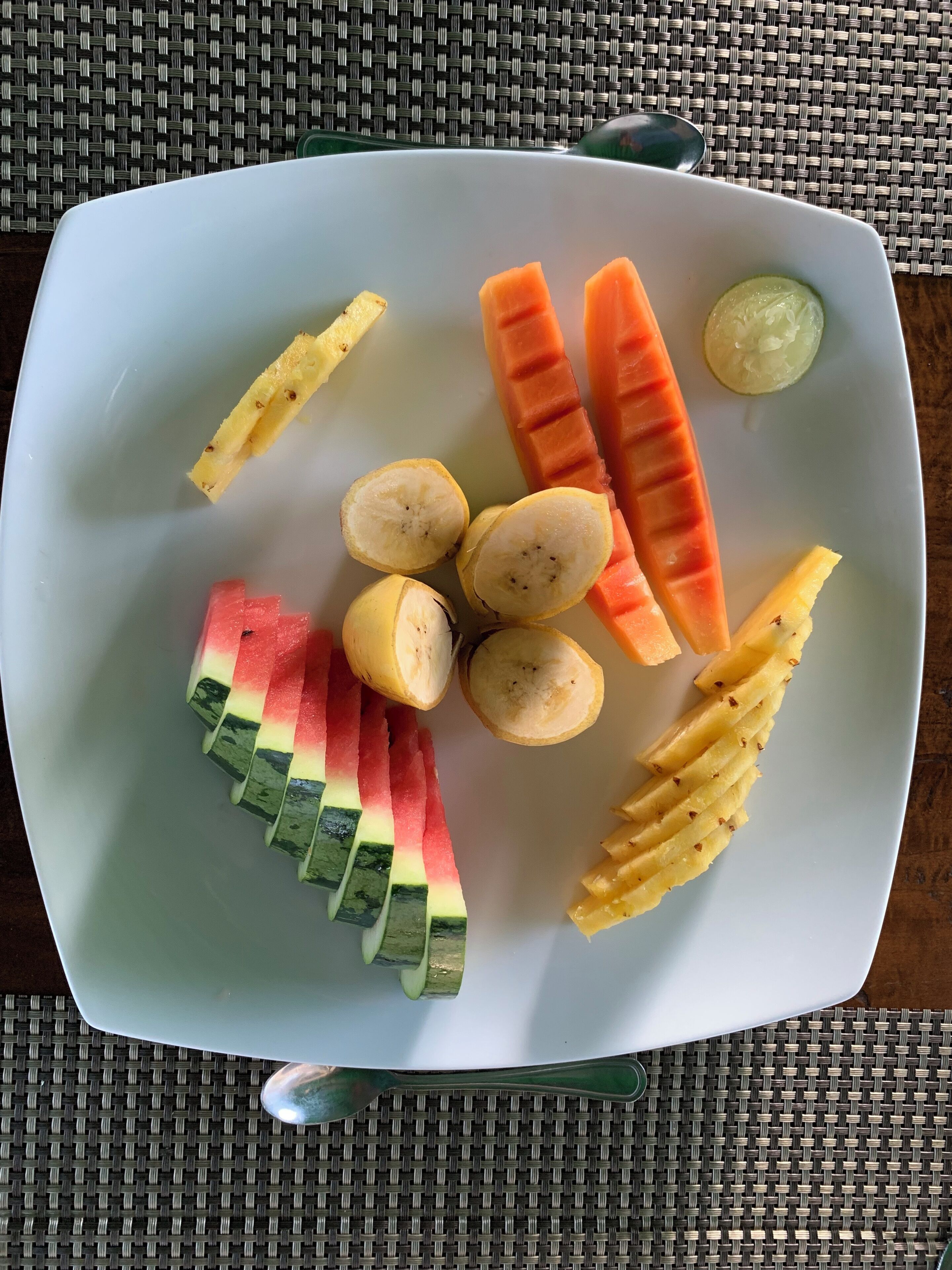 Une assiette blanche contenant des fruits et des légumes coupés en tranches.
