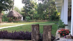 A garden with a thatched-roof structure, a pathway, and a stone wall with plants. - Sigiriya Rock Hide (Sigiriya)