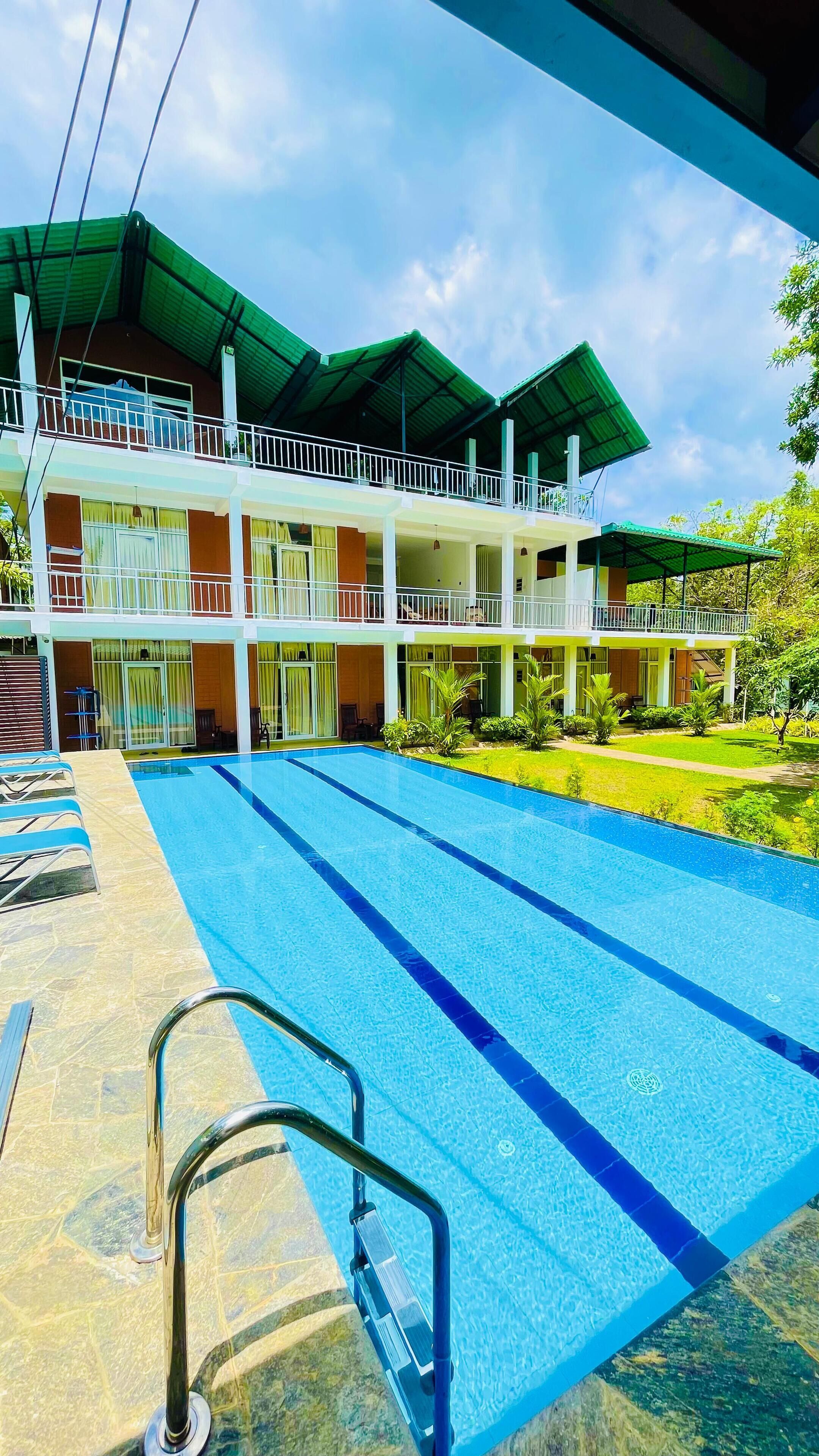 A hotel with a swimming pool, multiple balconies, and a well-maintained garden.