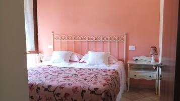 A bedroom with a bed, bedside tables, and a door.