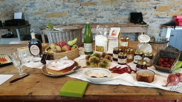 Una mesa de madera con diversos alimentos, una botella de vino y una cesta de frutas.