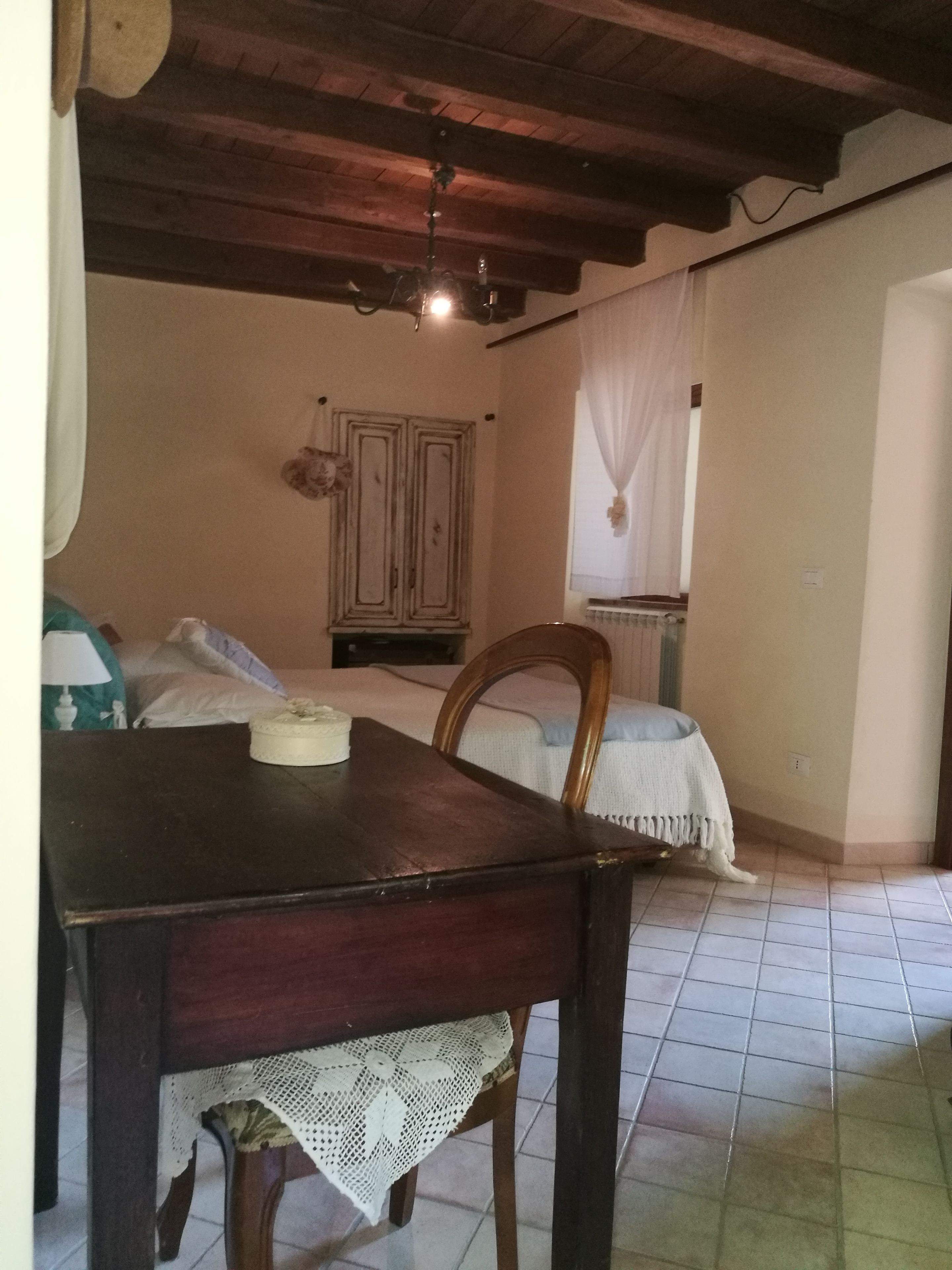 A room with a wooden table, a chair, a cabinet, and a window with curtains.