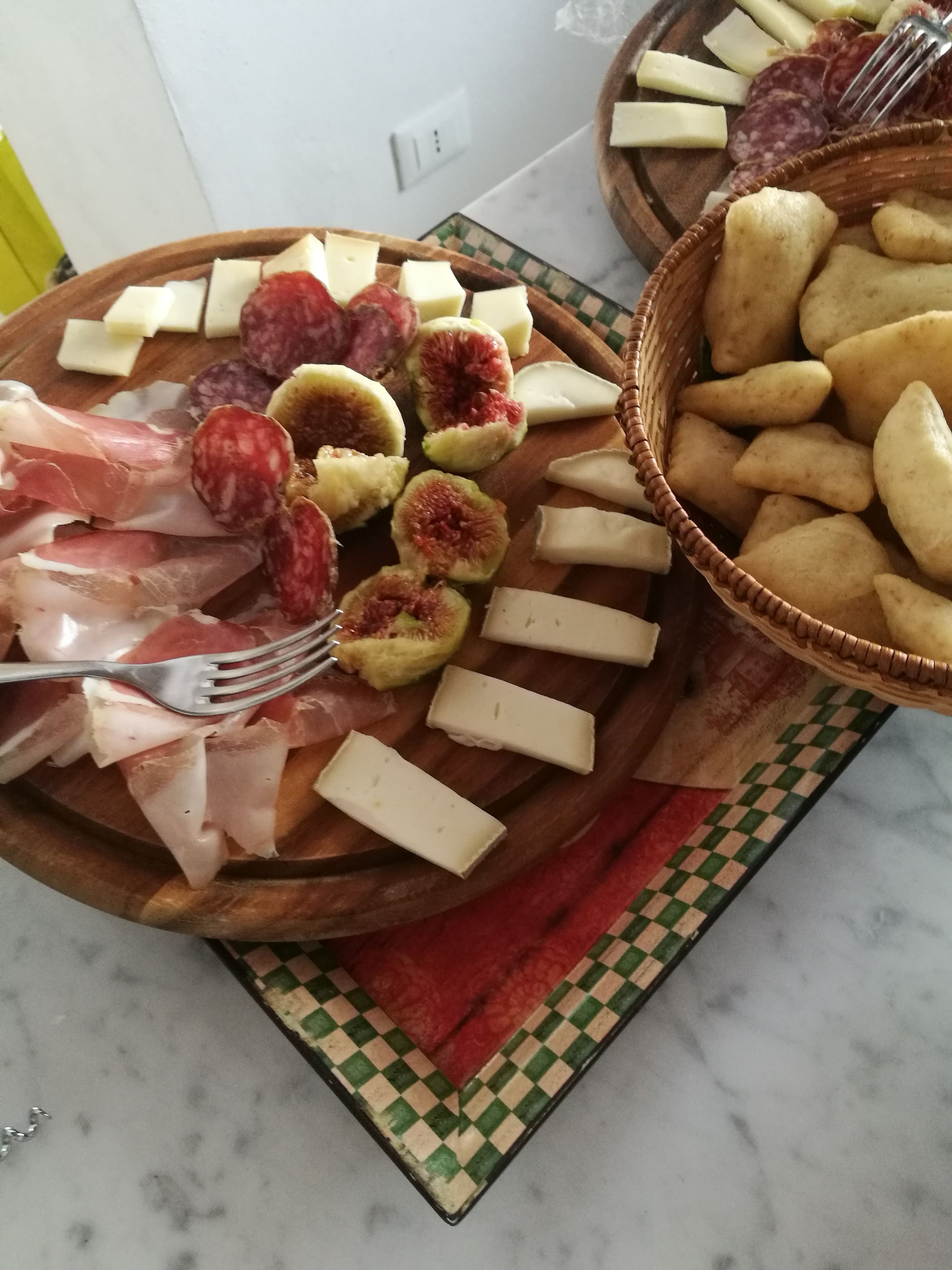 Un tagliere con diversi formaggi, salumi e fichi.