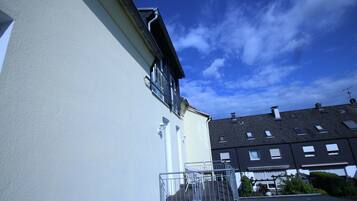 Ein Wohngebäude mit Balkon und Fenster vor blauem Himmel.