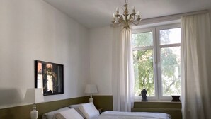 A bedroom with a bed, a nightstand, a lamp, a picture on the wall, and a window with curtains. - a-domo Apartments Oberhausen - Studio Apartments & Flats - short or longterm - single or grouptravel (Oberhausen)