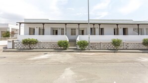 A white building with a symmetrical facade, a central entrance with steps, and a flat roof.