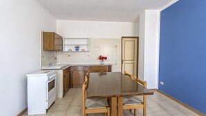 A compact kitchen with white cabinets, a wooden dining table, and a blue accent wall.