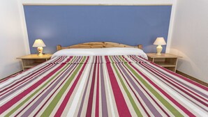 A bed with a striped bedspread, two bedside lamps, and a wooden headboard.