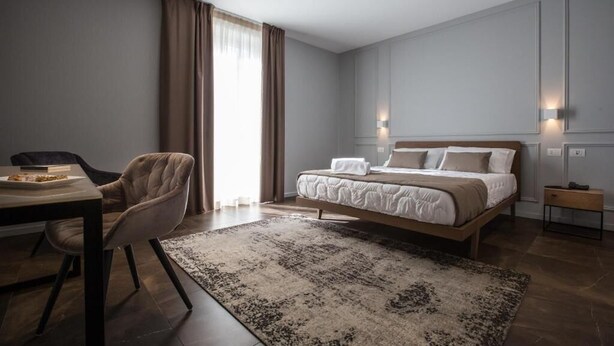 Ein modernes Hotelzimmer mit einem großen Bett, einem Schreibtisch und einem Sessel.