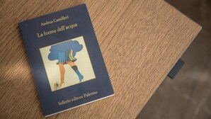 Ein Buch mit dem Titel „La forma dell'acqua“ von Andrea Camilleri auf einer Holztischplatte.
