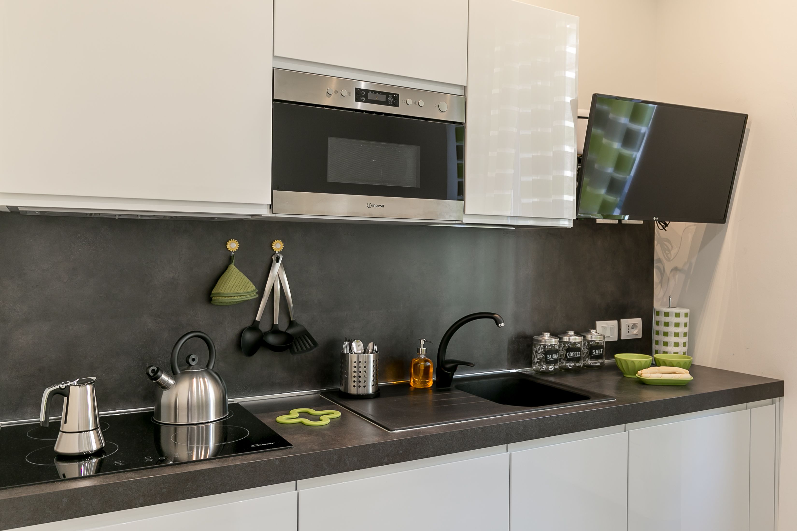 A modern kitchen with a built-in oven, a flat-screen TV, and stainless steel appliances.