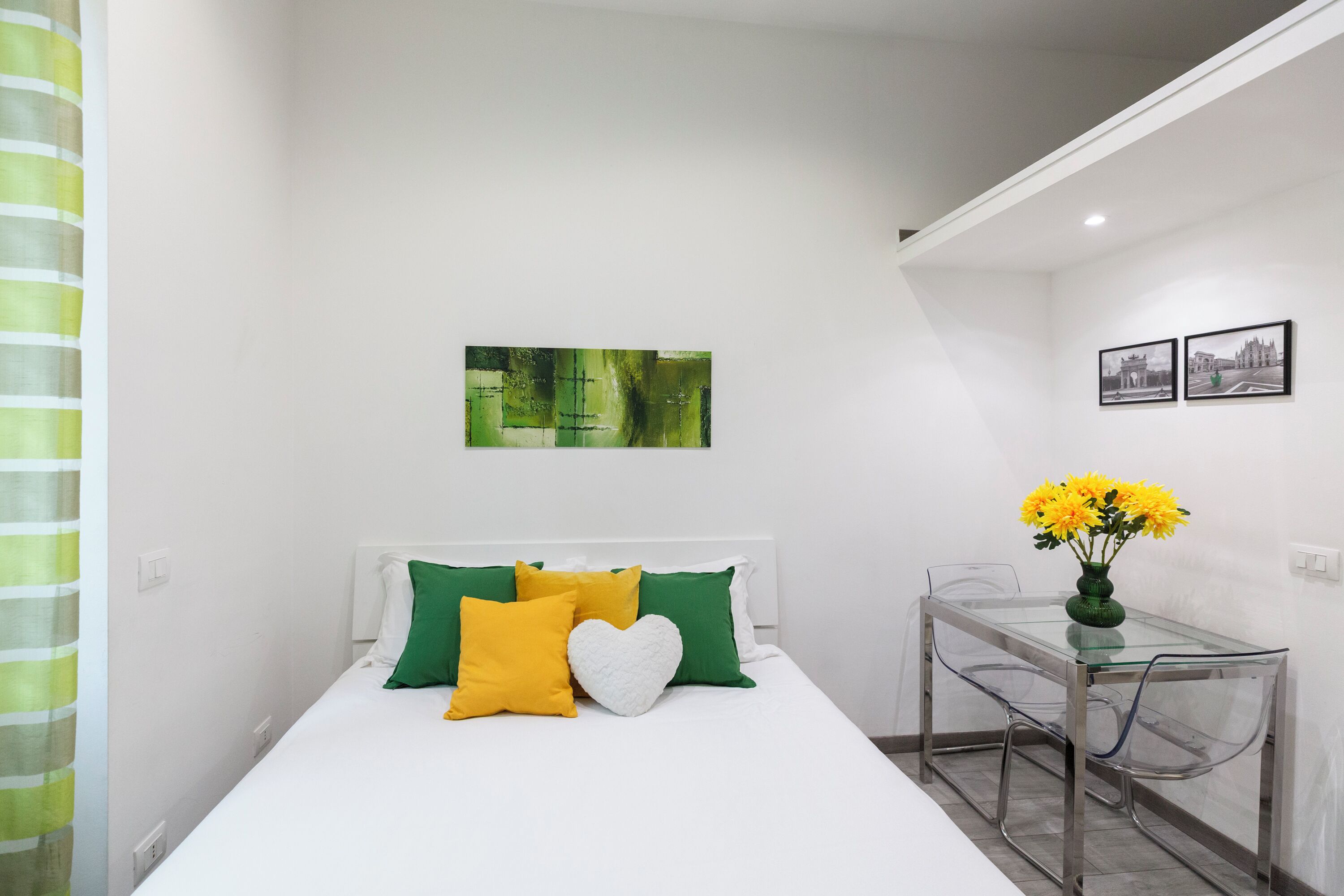 A hotel room with a bed, a glass table, and a vase with flowers.