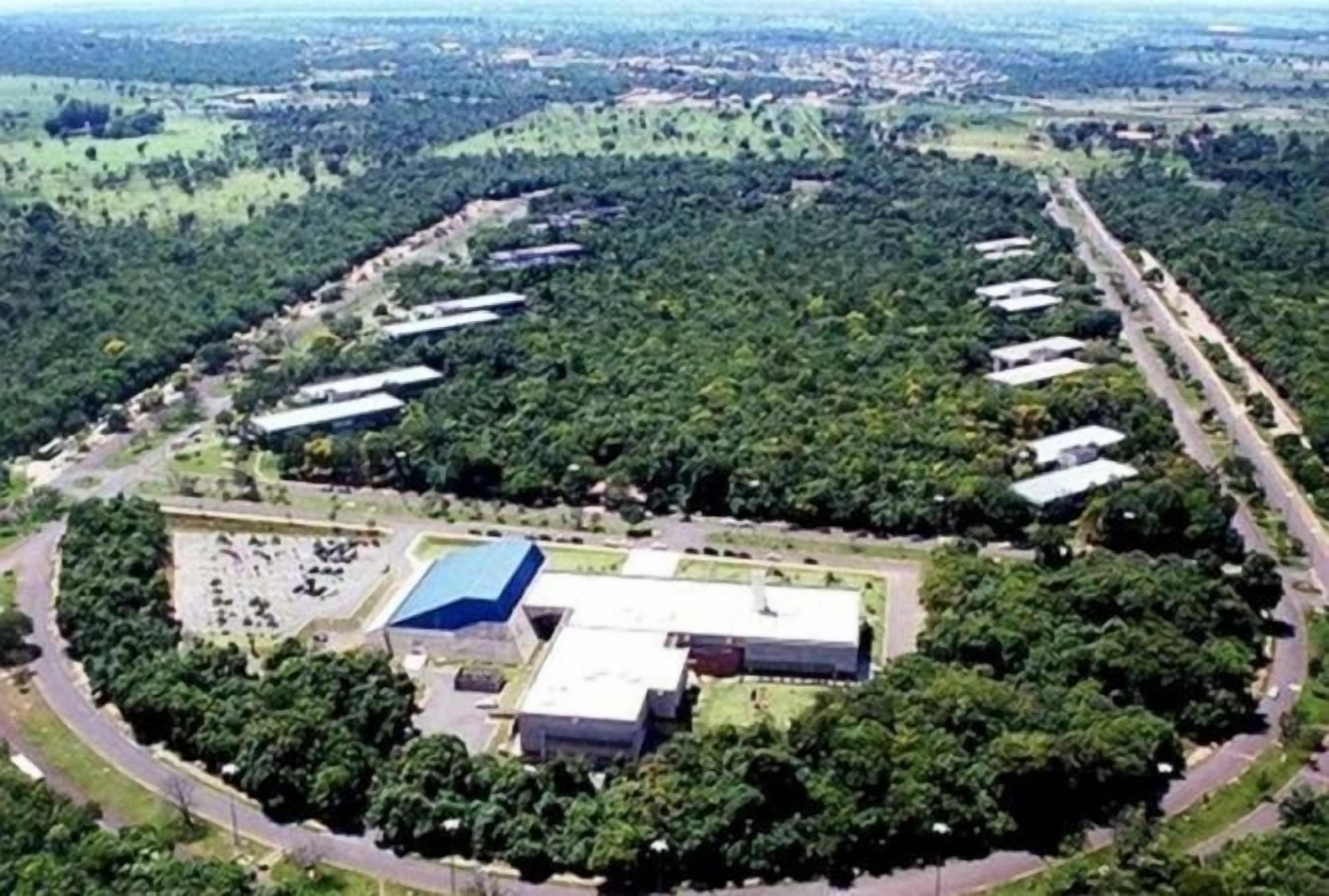 An industrial area with multiple buildings, roads, and surrounding greenery.