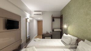 Een hotelkamer met twee bedden, een televisie, een bureau en een kledingkast.