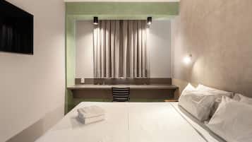 A modern hotel room with a bed, a desk, and a chair.
