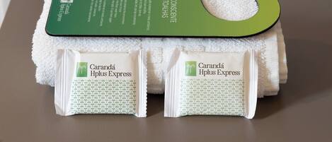 A green and white towel set with a hanging tag and two packaged products labeled "Caranda Hplus Express".