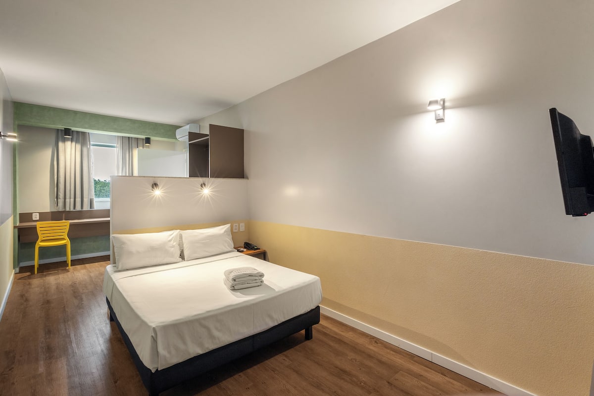 A modern hotel room with a bed, a desk, and a chair.