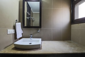 A bathroom with a white sink, a mirror, and a towel hanging on a rack.