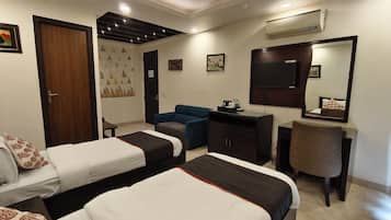 A hotel room with two beds, a desk, a chair, a wardrobe, a ceiling fan, and a large mirror.