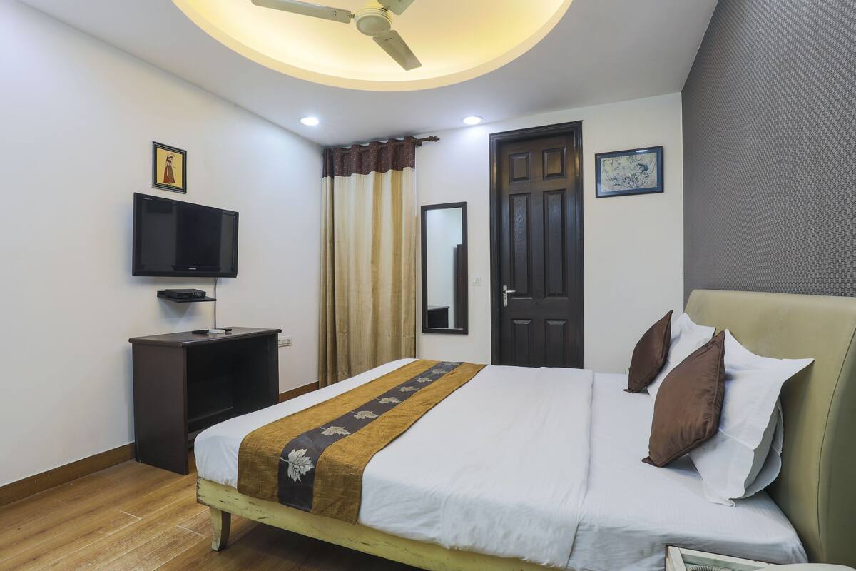 Una camera d'albergo ordinata con un letto, una televisione, un armadio e una porta.