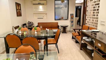 A dining area with a glass table, brown leather chairs, and a wooden buffet.