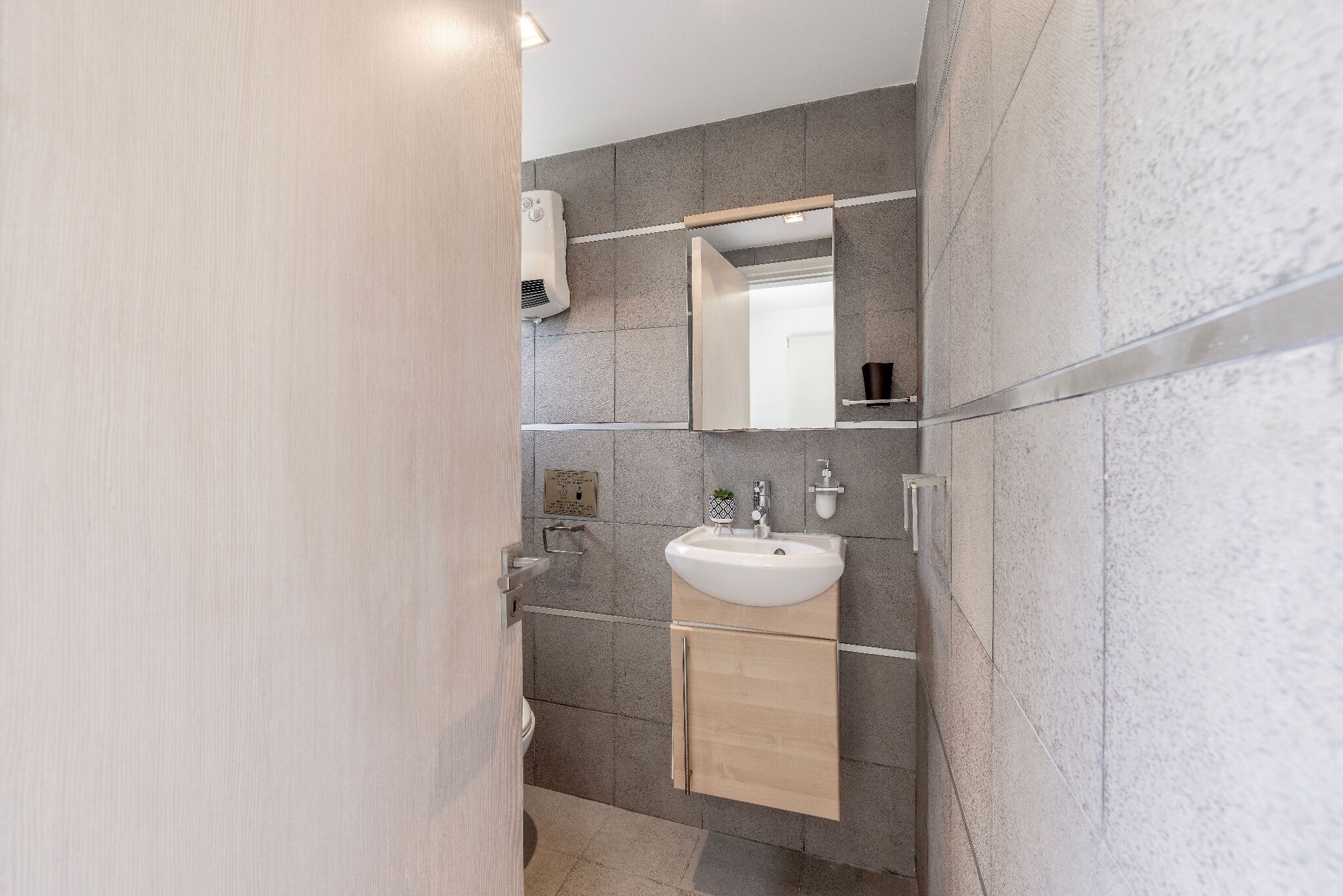 Een moderne badkamer met een wit wastafel, spiegel en handdoekrek.