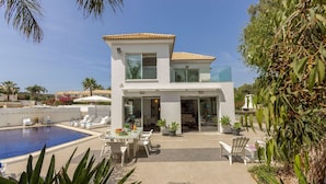 A modern two-story house with a swimming pool, outdoor seating, and lush greenery. - Villa Hibiscus is a unique and spectacular four bedroom villa in an residential gated cul de sac (Protaras)