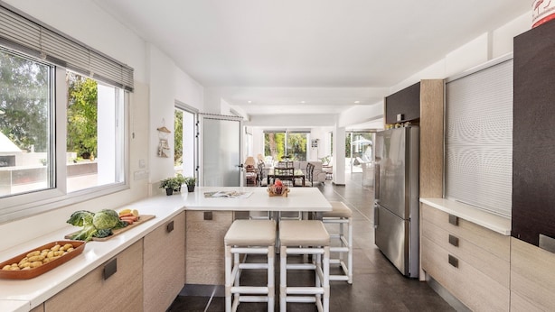A modern kitchen with a central island, bar stools, and a refrigerator. - Villa Hibiscus is a unique and spectacular four bedroom villa in an residential gated cul de sac (Protaras)