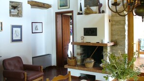 A living room with a fireplace, a brown leather chair, and various wall decorations. - House in the paradise garden above v. Gargnano for individuals u. Children (Gargnano)