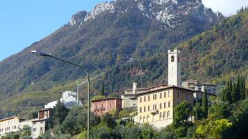 A town with buildings and a prominent tower, surrounded by mountains and trees.