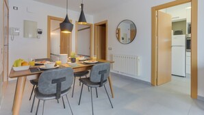 Un comedor moderno con una mesa de madera, cuatro sillas grises e iluminación colgante.