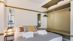 Un dormitorio moderno con cama, mesita de noche y vestidor.