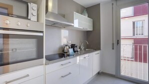 Una cocina moderna con gabinetes blancos, horno empotrado y campana de acero inoxidable.