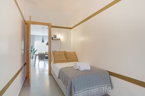 Een slaapkamer met een bed, nachtkastje, lamp en een deur naar een badkamer.