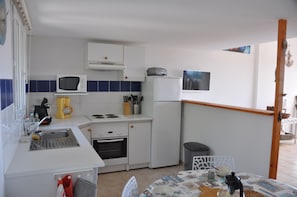 Kompakti keittiö, jossa on mikroaaltouuni, liesi, pesuallas ja jääkaappi.