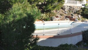 A residential area with a swimming pool, white fences, and a large pine tree. - Pavilion with terrace sea view and pool in residence (SAINT PIERRE LA MER)