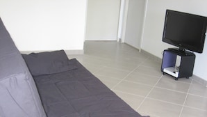 A room with a grey sofa, a television on a stand, and a tiled floor. - MATHES la PALMYRE house WOOD (BBC label) (Les Mathes)