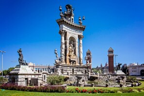 Un monumento histórico con estatuas, una fuente y un cielo azul despejado.