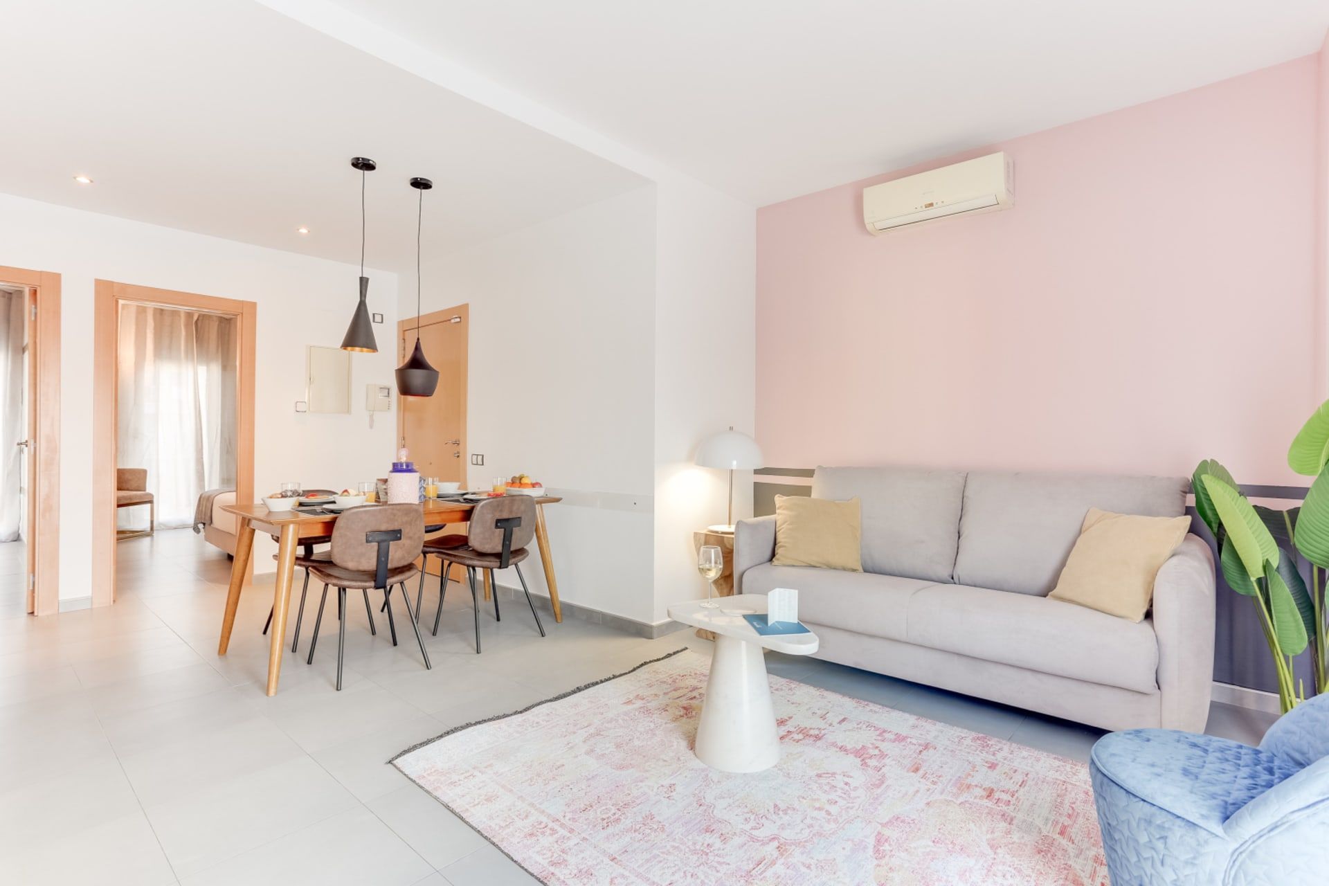 A modern living room with a sofa, a dining area with chairs, and a coffee table.