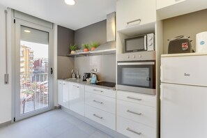 Una cocina moderna con armarios blancos, microondas, horno y refrigerador.