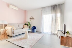 Una sala de estar moderna con un sofá, una mesa de centro y un televisor sobre un mueble de madera.