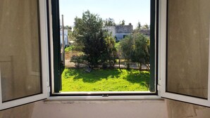A window with a view of a grassy area and trees. - Appartamento Acton - Piano Terra (Ugento)