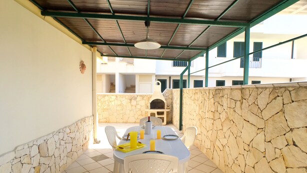 A covered outdoor dining area with stone walls and a tiled floor. - Appartamento Acton - Piano Terra (Ugento)