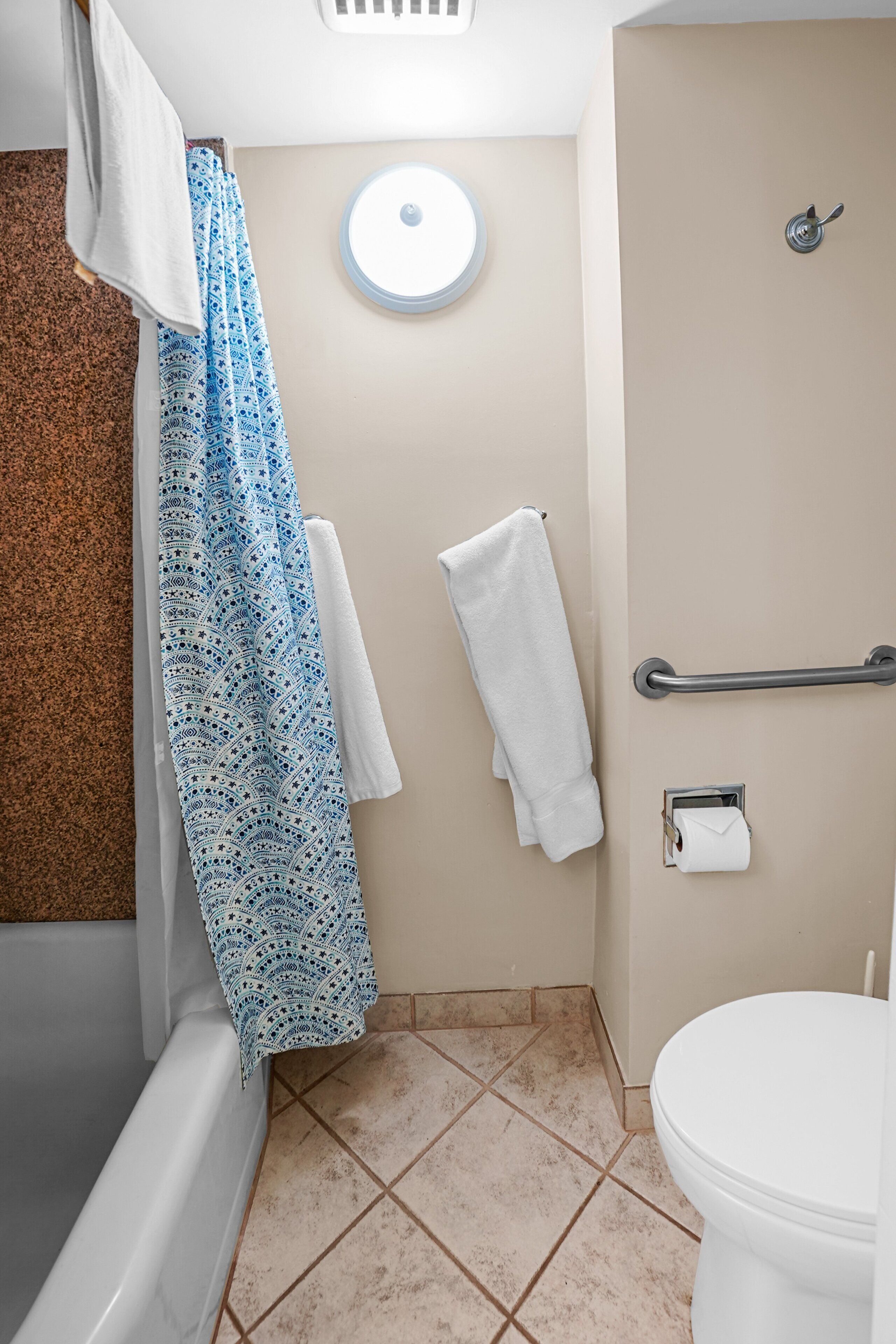 Bagno con vasca, servizi igienici, doccia con porta asciugamani e mancorrente.