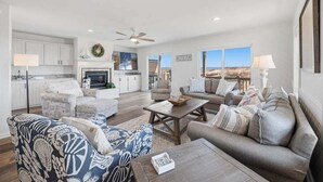 A spacious living area with a fireplace, a dining table, and a sofa set. - Salt Therapy OBX | Oceanfront | Dog Friendly, Hot Tub | Nags Head (Nags Head)