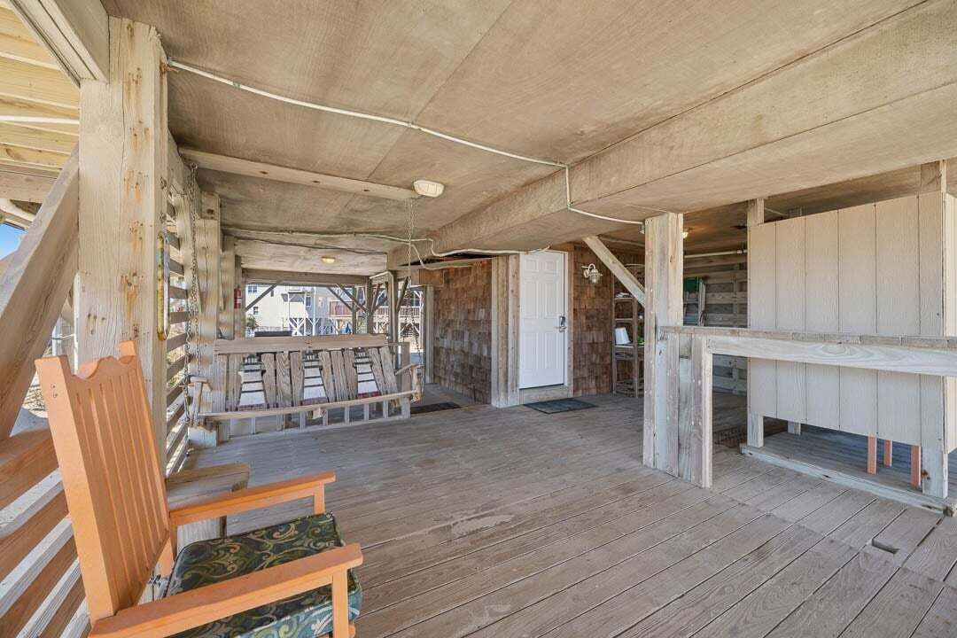 Eine Holzterrasse mit einer Bank, einem Tisch und einer Treppe, die zu einer erhöhten Ebene führt.
